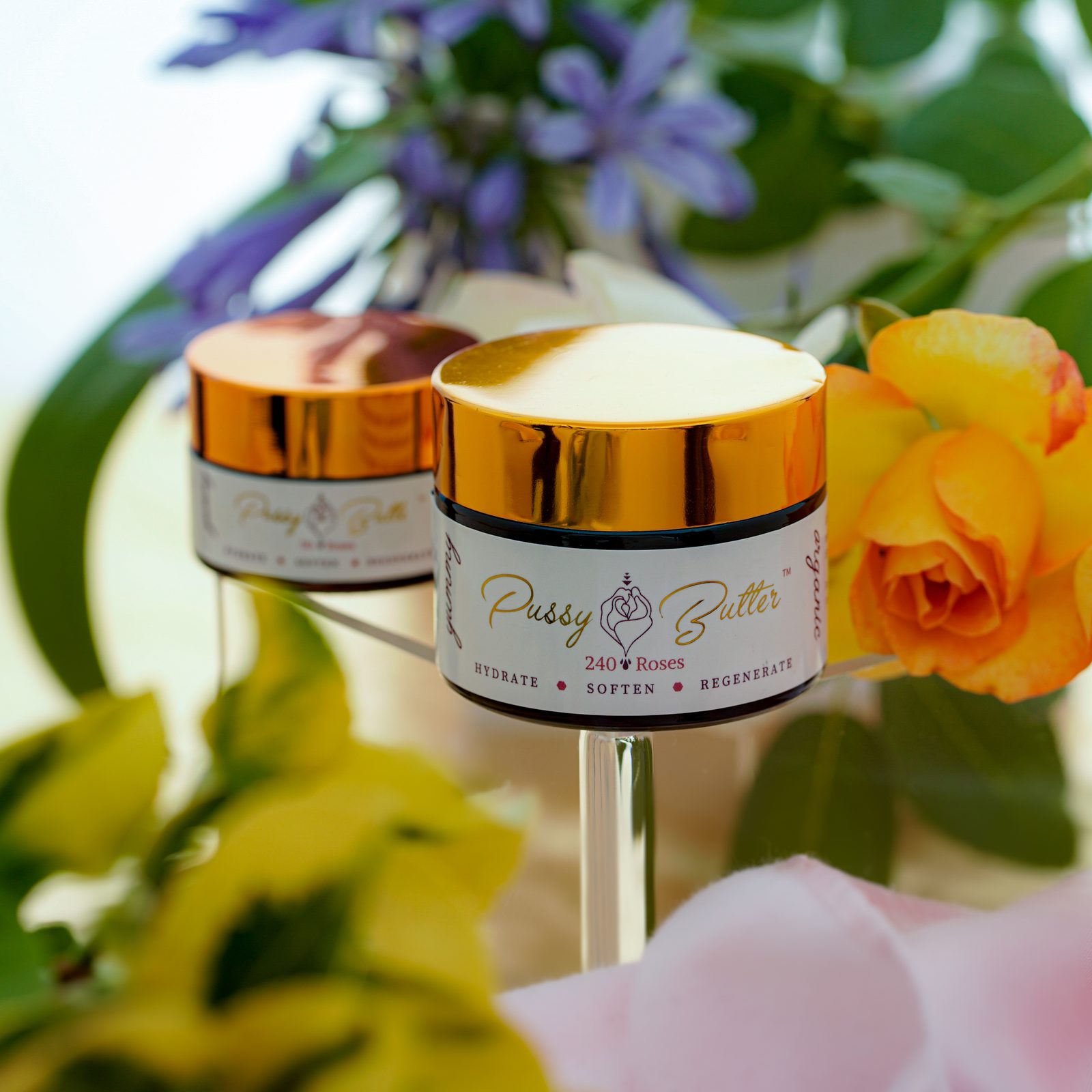 Two jars of Pussy Butter™ among fresh flowers