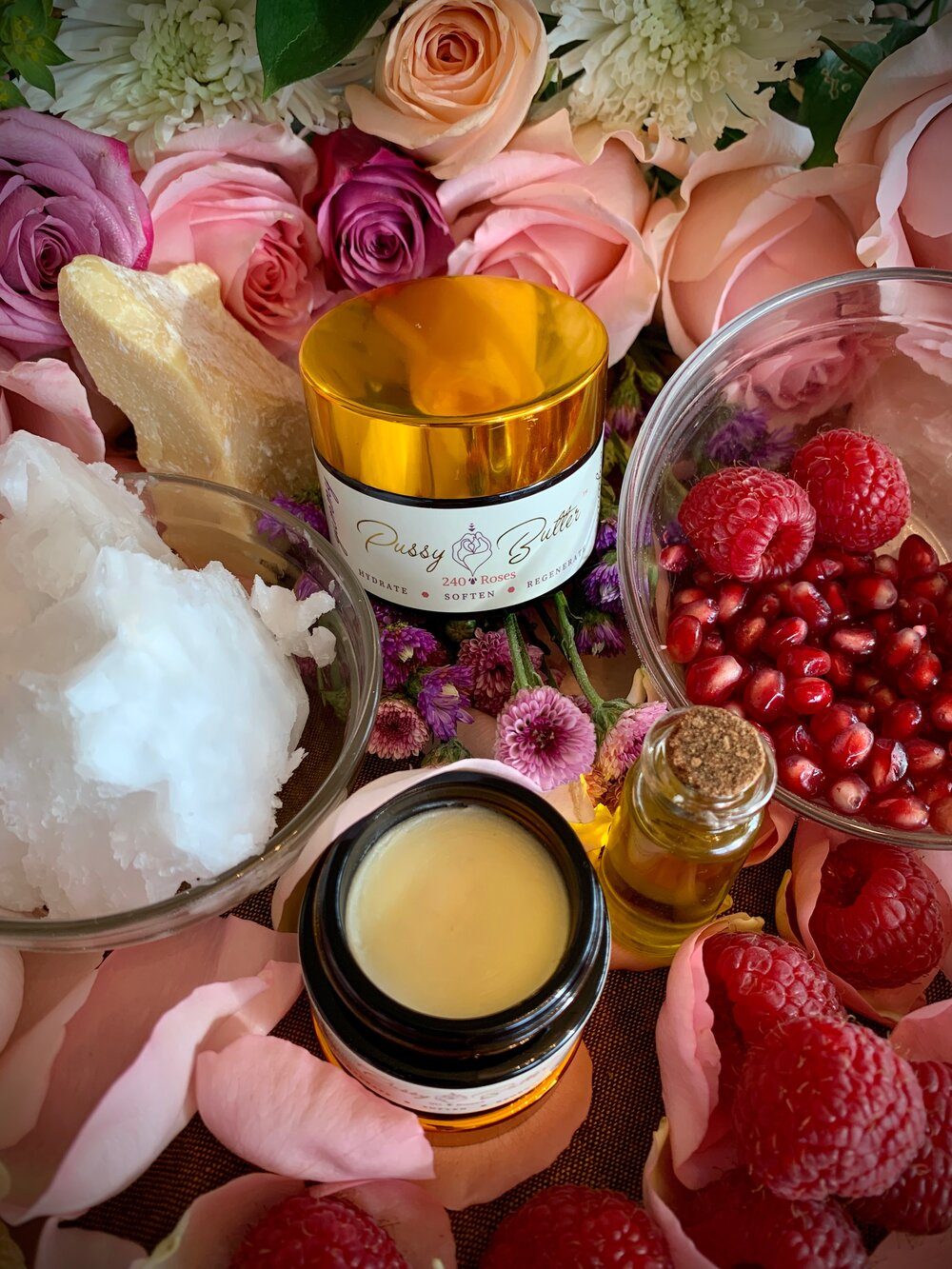 Pussy Butter™ surrounded by its organic ingredients — coconut, cacao, raspberry, pomegranate and rose